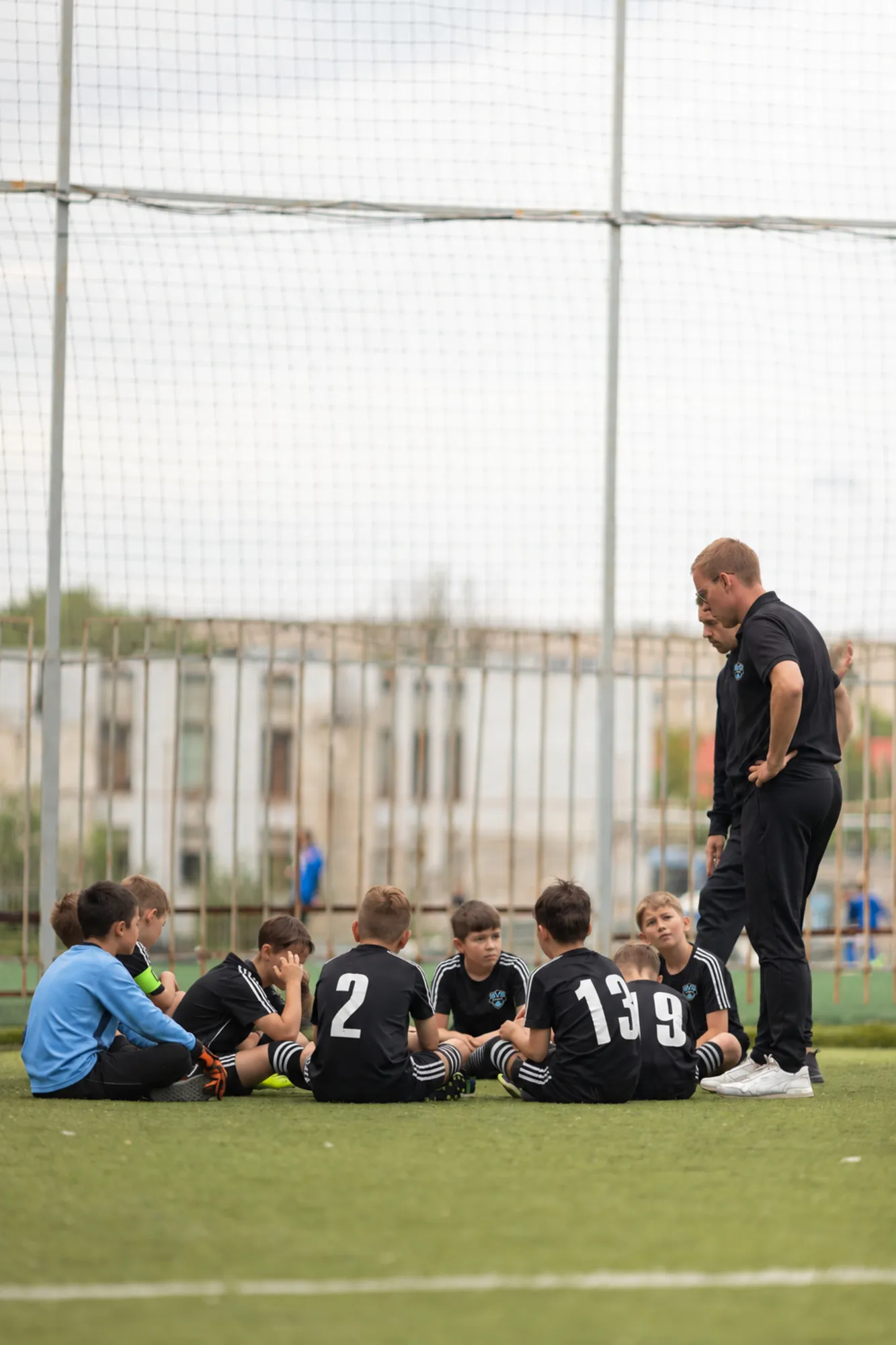 Coach talking to a group of young players seated on the field