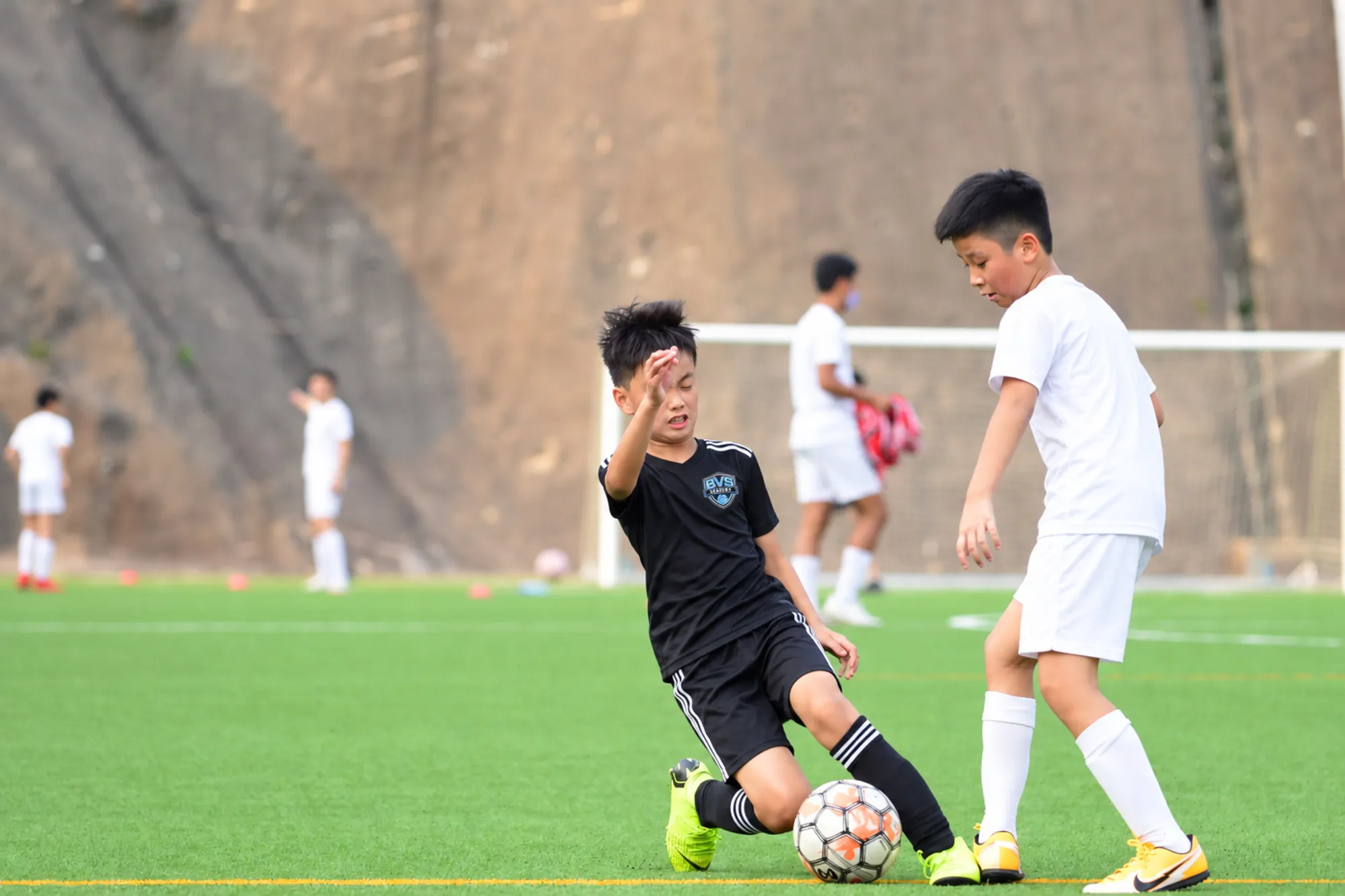 Young players competing for the ball on artificial turf