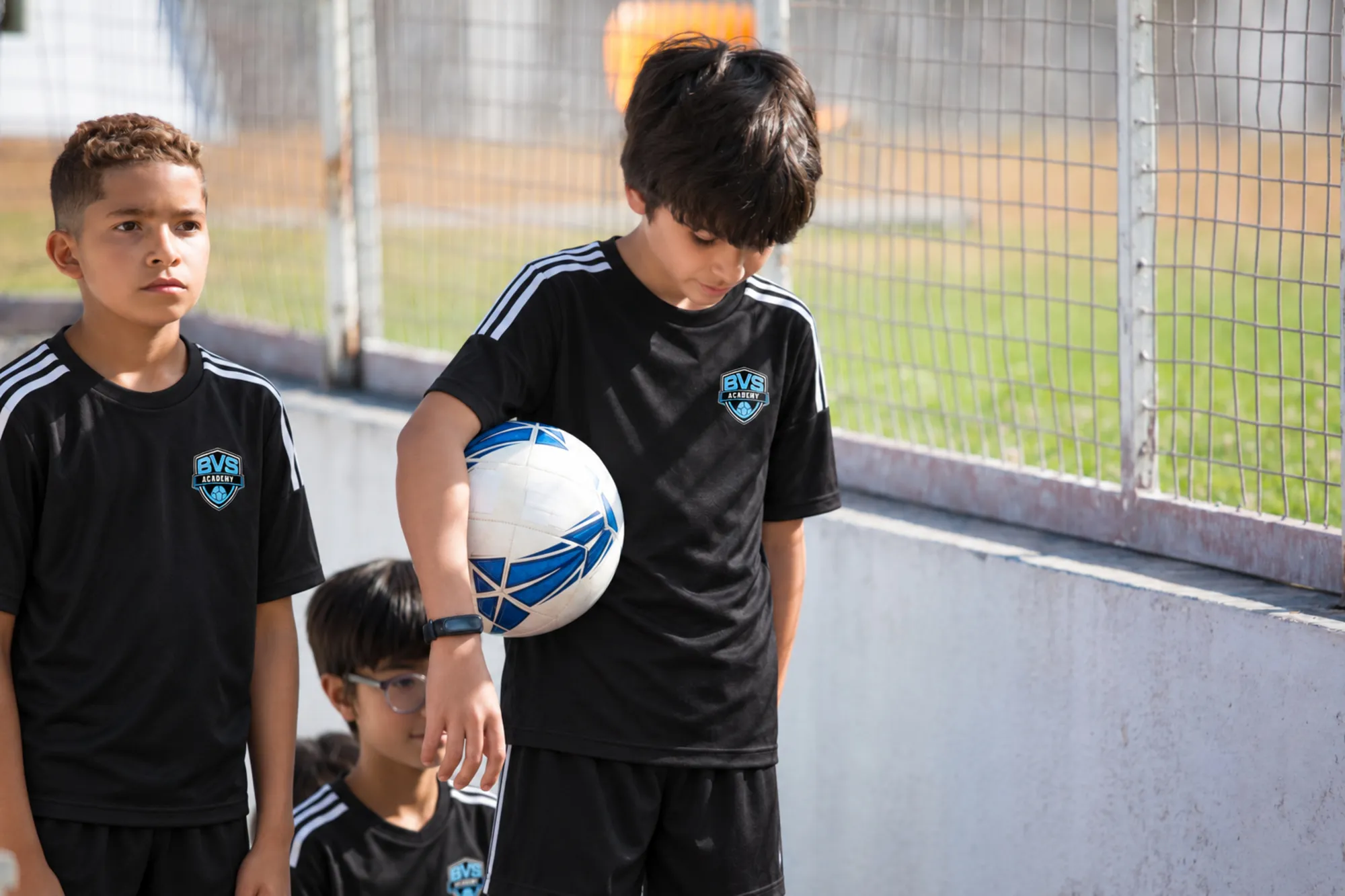 Young players in blue kits posing with a soccer ball